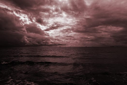 Dramatic evening seascape in dark burgundy colors. Purple sky with clouds over the sea. High quality photo