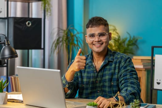 Like. Smiling Indian businessman looking approvingly at camera showing double thumbs up sign positive something good great news positive feedback. Happy Hispanic guy at home office desk. Lifestyle