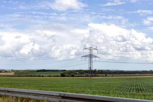 Electricity concept. High voltage power line pylons, electrical tower on a green field with blue sky. High quality photo