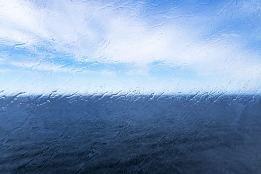 Raindrops on the window overlooking the sea. Background with sea and sky on a rainy day. High quality photo