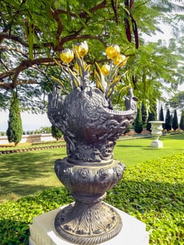 Garden decoration sculpture vase with golden flowers. High quality photo