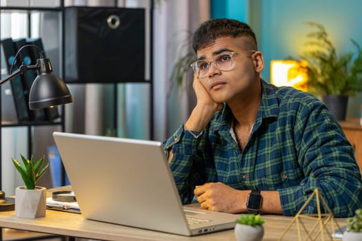 Sad frustrated pensive Indian man unrequited love suffers from unfair situation bankruptcy. Problem, break up depressed feeling bad annoyed burnout stress. Guy at home office desk workplace. Lifestyle