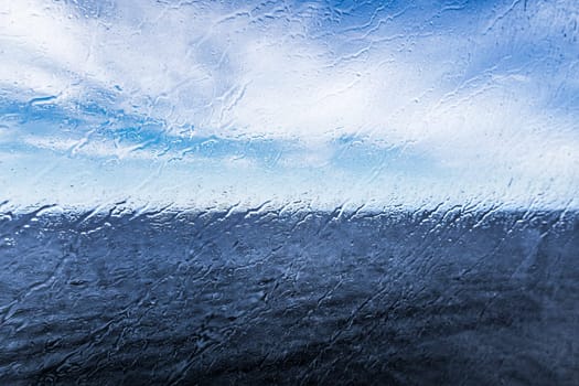 Raindrops on the window overlooking the sea. Background with sea and sky on a rainy day. High quality photo