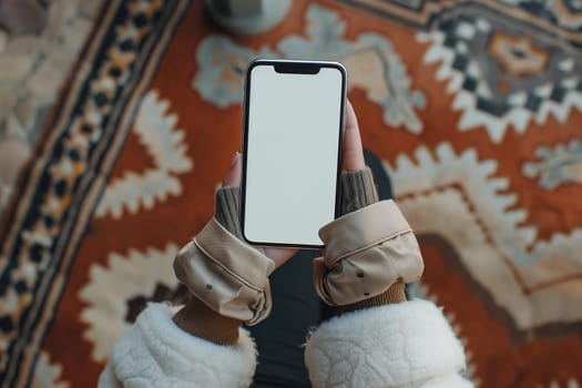 A womans hand holding an Phone while sitting on a rug. Mockup