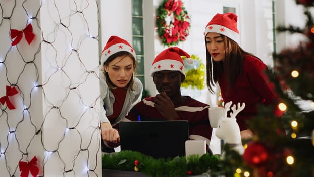 Team leader in Christmas decorated office delegating tasks to staff members before winter holiday season. Manager teaching company personnel how to properly finish project in xmas adorn workspace