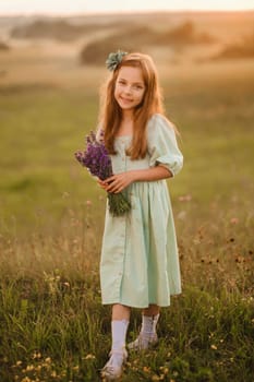 a little girl in a light green dress with a bouquet of lavender in a field at sunset.