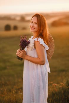 A girl in a white dress with a bouquet of lavender flowers stands in a field at sunset.