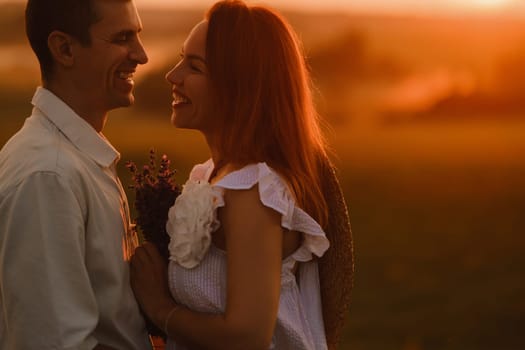 A couple in love in white clothes in a field at a red sunset.