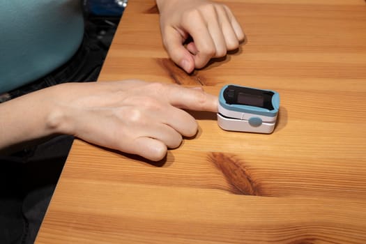 Person Uses Pulse Oximeter Measuring Oxygen Saturation In Blood And Heart Rate. Pulse Oximeter On The Woman's Hand. Healthcare, Disease Prevention. Horizontal Plane. High quality photo