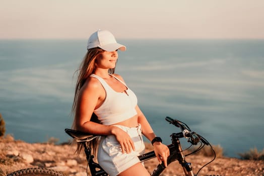 A woman cyclist on a mountain bike looking at the landscape sea. Adventure travel on bike