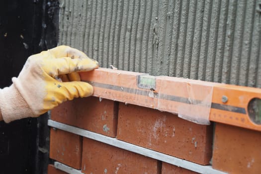 Individual is using a level to assess the plumb of a brick wall,