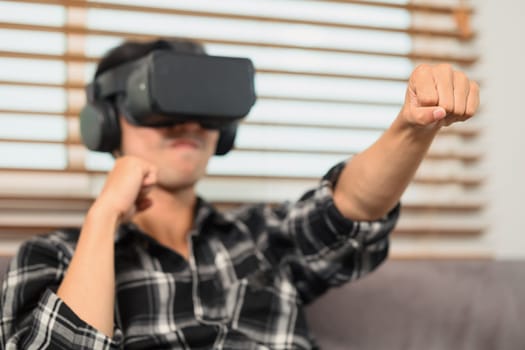 Excited man with VR headset playing boxing game and throwing punches in the air.