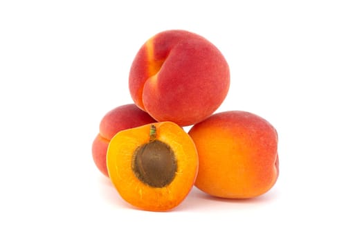 Pile of ripe apricots and one sliced in half to showcase its succulent interior, isolated on a white background