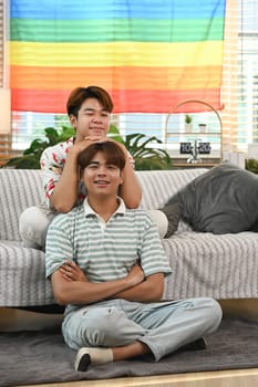 Cheerful young gay couple relaxing at home enjoying free time. LGBTQ people lifestyle concept.