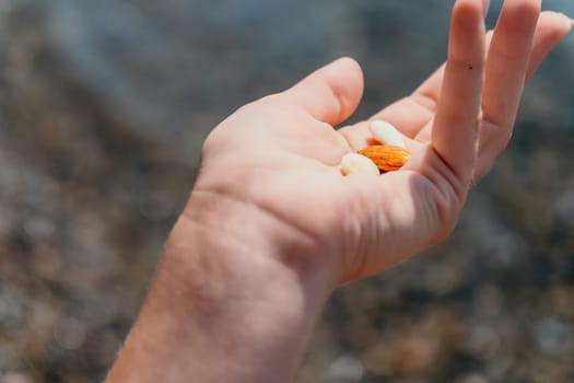 Woman eating milky almond nuts. A young caucasian woman choping fresh green almond after morning fitness yoga near sea. Only hands are visibly. Healthy vegan food. Slow motion. Close up