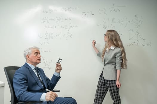 Female student answers a question from an elderly professor at a white board
