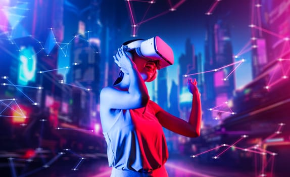 Female standing in virtual reality cyberpunk style building wear VR headset connecting metaverse, future cyberspace community technology, Woman dancing raising one arm holding goggle. Hallucination.
