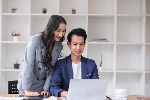 A young businessman and a female Asian accountant are discussing financial accounting and business planning together in the office..