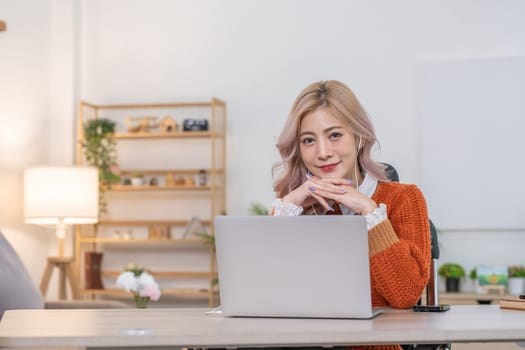 Beautiful young accountant wearing headphones holds financial meeting with company team online with laptop from home..