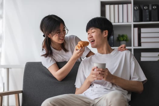 Young couple sitting together on the sofa in the living room Have coffee and snacks together..