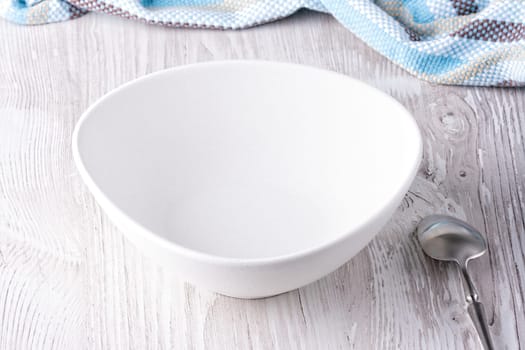 Empty bowl and spoon on wooden table.