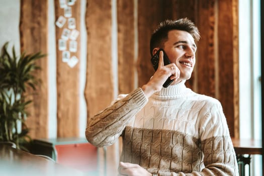 man is engaged in a phone conversation, holding a cell phone to her ear. he appears focused and attentive. The background shows a nondescript urban setting.