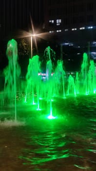 fountain at night in the city, green water color. High quality photo