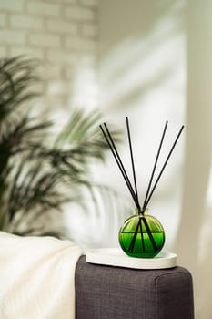 Aroma diffuser bottle with sticks in living room, close up