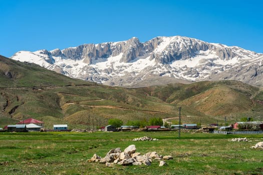 The lush green Sobucimen plateau in spring and the mountains with some melted snow behind.