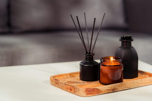 Aromatic reed freshener and candle on table in room close up