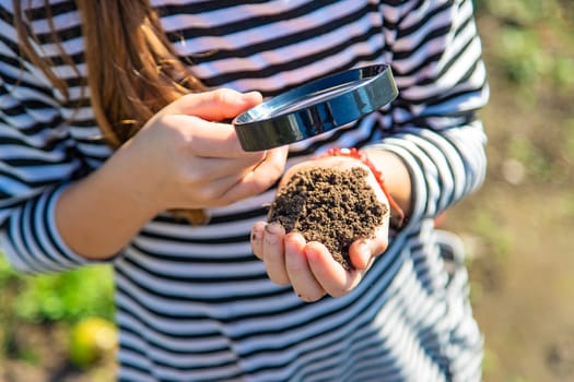 Children examine the soil with a magnifying glass. Selective focus. Kid.