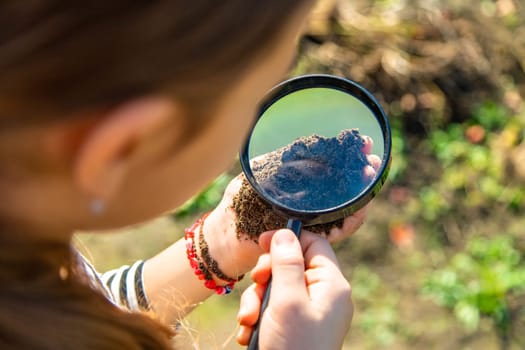 Children examine the soil with a magnifying glass. Selective focus. Kid.