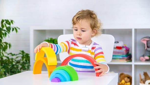 The child collects the constructor rainbow. Selective focus. Kid.