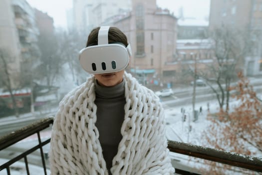 Winter vistas surround a girl experiencing VR on the balcony with a headset. High quality photo