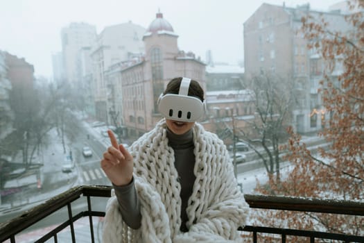 Winter scenes unfold as a girl experiences VR on the balcony with a headset. High quality photo