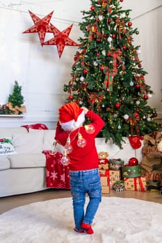 A child dances near a Christmas tree with a garland. Selective focus. Kid.