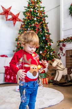 A child dances near a Christmas tree with a garland. Selective focus. Kid.