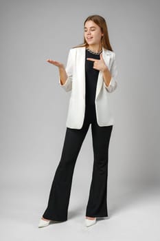 Confident Young Businesswoman Presenting With Hand Gesture in Studio Setting copy space