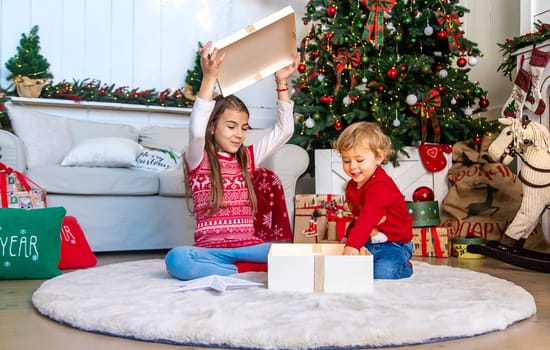 Children open Christmas gifts under the tree. Selective focus. Kid.