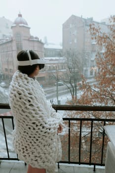 Amidst snowy landscapes, a young lady enjoys VR on the balcony with a headset. High quality photo