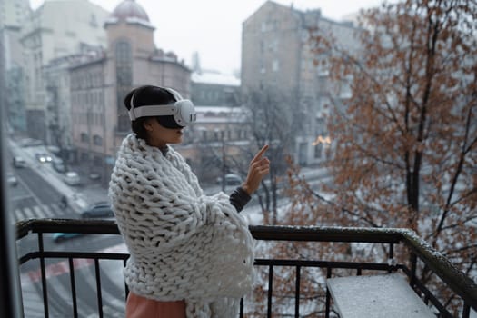 A radiant young woman enjoys the winter cityscape through her virtual reality glasses. High quality photo