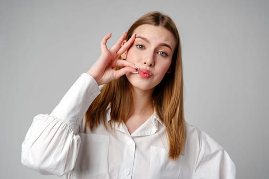 Young Woman Making a Hush Gesture on gray background in studio