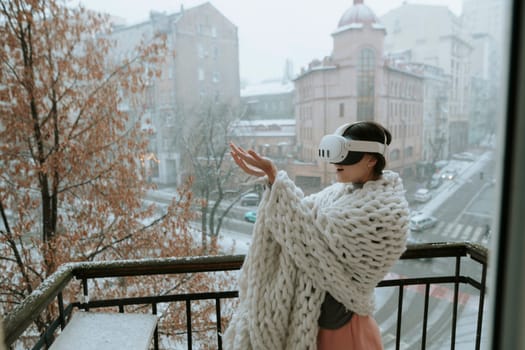 A charming woman in VR glasses marvels at the winter city scene around her. High quality photo
