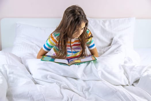 Children read a book in bed. Selective focus. Kid.