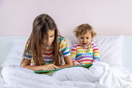 Children read a book in bed. Selective focus. Kid.