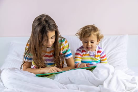 Children read a book in bed. Selective focus. Kid.