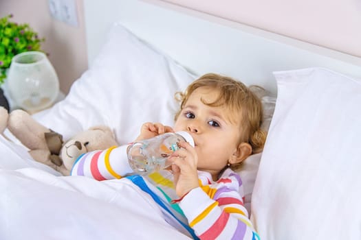 A child drinks from a bottle in bed. Selective focus. Kid.