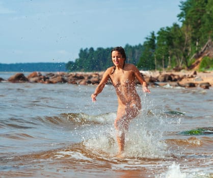 Young beautiful woman posing nude on the seaside enjoying the sea and nature