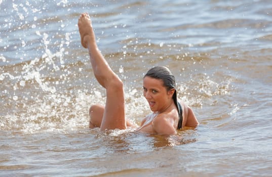 Young beautiful woman posing nude on the seaside enjoying the sea and nature