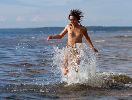 Young beautiful woman posing nude on the seaside enjoying the sea and nature